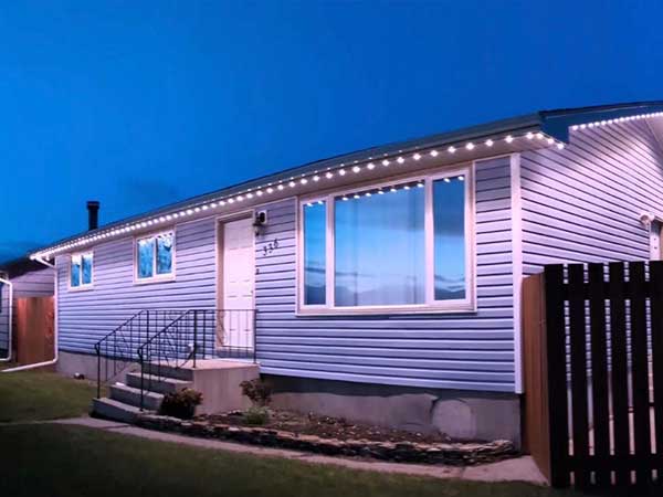 houselights Single-story house illuminated by bright LED lights along the roofline, creating a clean and modern appearance during twilight.