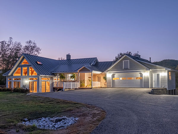 modern-cozy-lit-house-against-a-cloudy-sky-in-the-2023-11-27-05-34-00-utc Elegant countryside home at dusk, illuminated by soft exterior lights highlighting the architectural details and creating a welcoming ambiance.