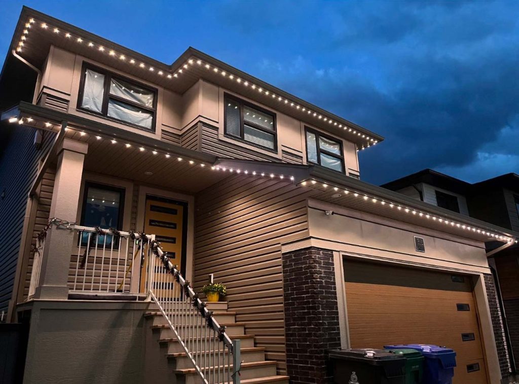 Modern two-story home at dusk, featuring clean architectural lines and bright LED lighting along the roofline, accentuating the house's exterior details and creating a welcoming atmosphere.