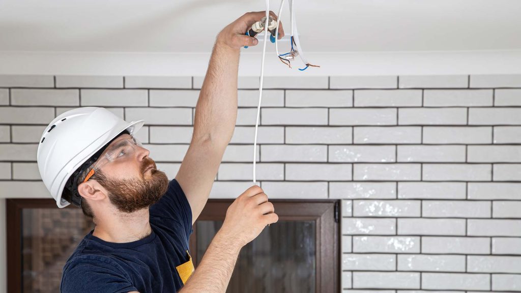 residential electrician wiring a light in the ceiling