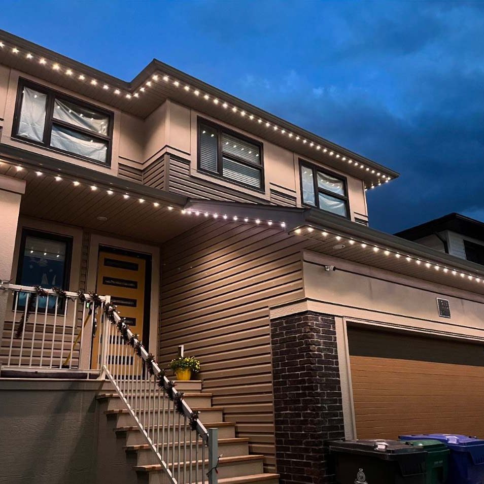 Modern two-story home at dusk, featuring clean architectural lines and bright LED lighting along the roofline, accentuating the house's exterior details and creating a welcoming atmosphere.